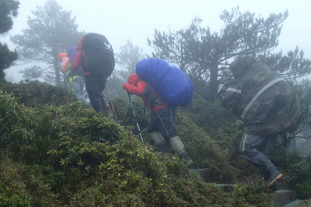 登山遇到降雨,請穿上兩截式雨衣褲,妥善固定背包套,做好防水。/玉管處提供